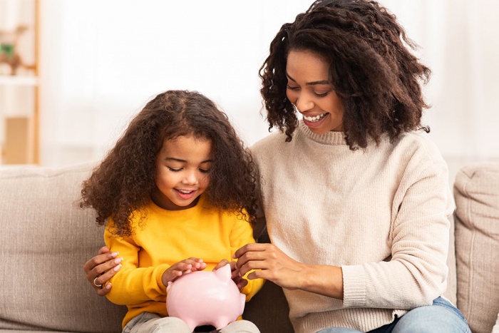woman and young girl with piggy bank