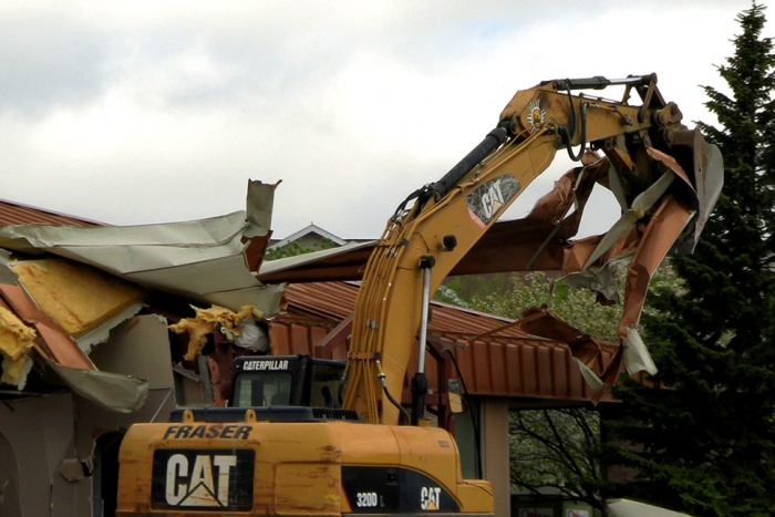 Bulldozer pulling roof off building