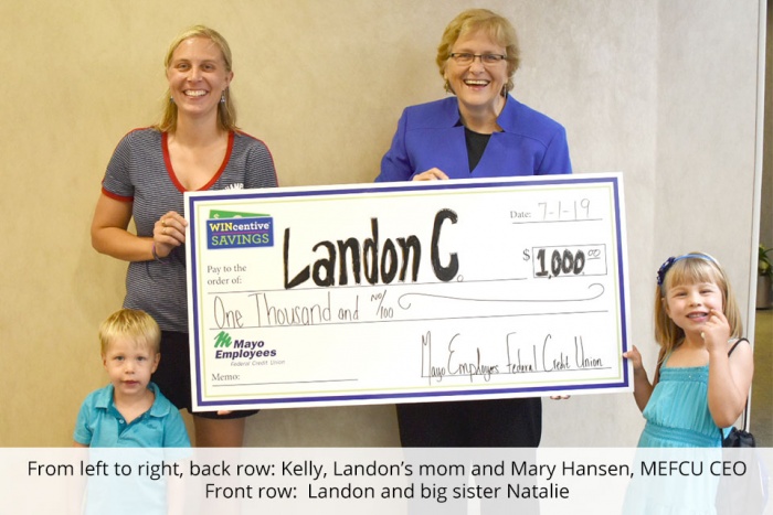 group of two adults and two children holding large check