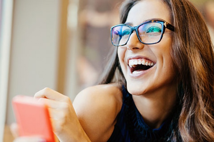 woman in glasses looking at something off camera and laughing